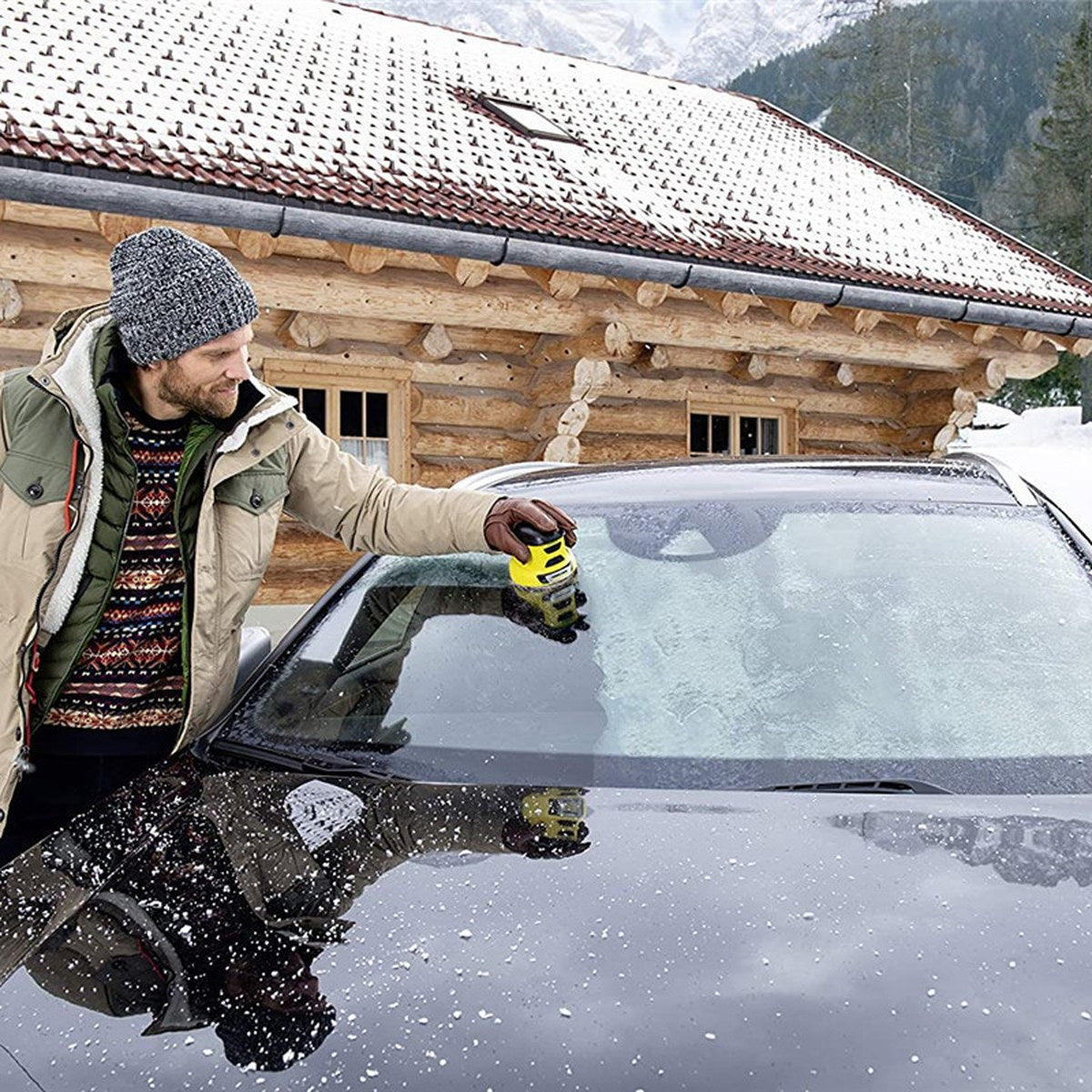 Un homme dégivre son pare-brise avec le ByeFrost Spin jaune